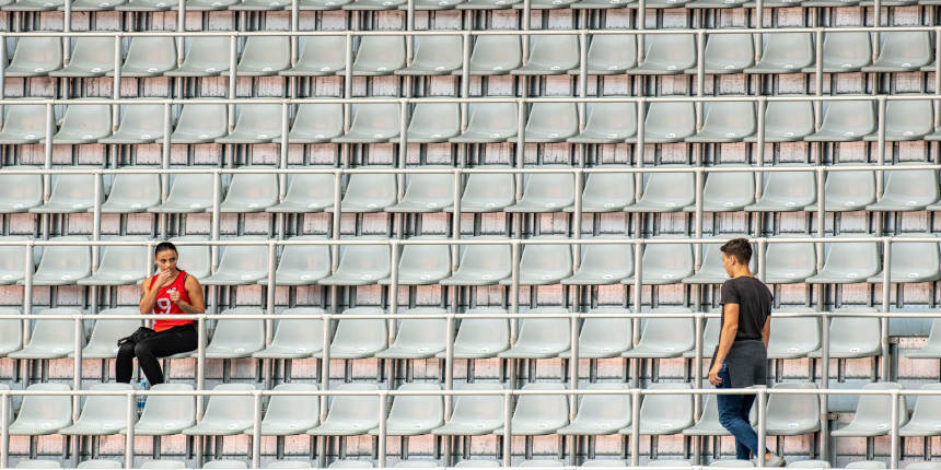 Una mujer sentada y un hombre caminando hacia suasiento en las gradas del estadio