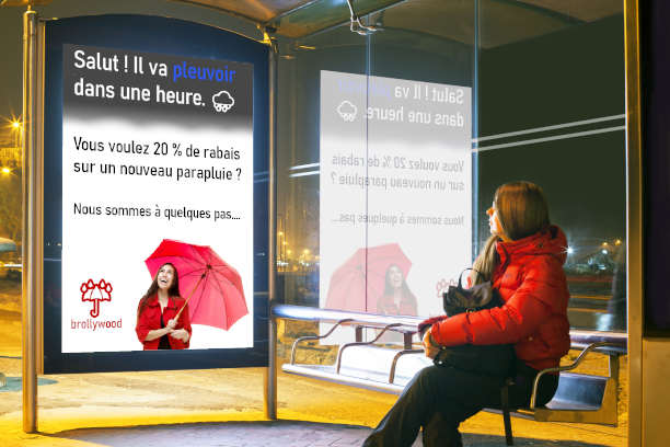 Une publicité sur un arrêt de bus biométrique faisant la promotion d'un magasin de parapluies à une personne attendant le bus.