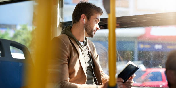 Photo recadrée d'un beau jeune homme lisant un livre pendant son trajet du matin en bus