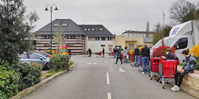 Clients faisant la queue devant un supermarché à cause du COVID-19