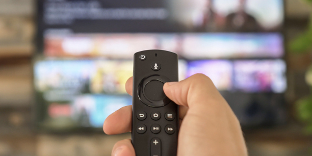Männliche Hand hält die TV-Fernbedienung und wechselt den Fernsehkanal. Kanalsurfen, konzentriert auf die Hand und die Fernbedienung. Internet-TV.