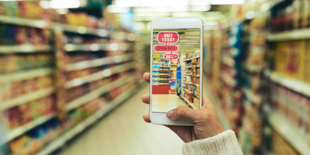 Nahaufnahme einer jungen Frau beim Einkaufen im Supermarkt mit Hilfe einer Augmented-Reality-App, unscharfer Hintergrund