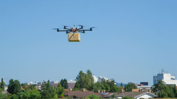 UAV drone carrying a brown parcel over a city