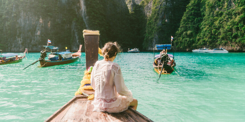Woman sitting on the deck of a small wooden boat in tropical waters
