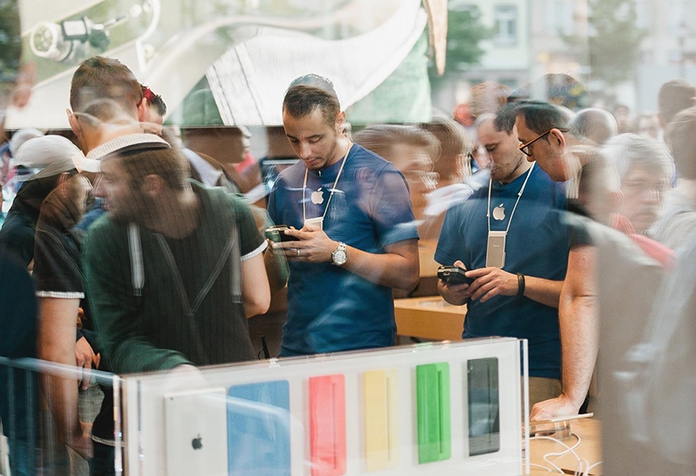Deux employés d'Apple vus à travers le reflet d'une fênetre sur une rue bondée