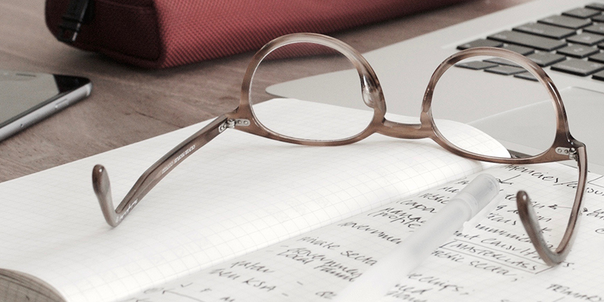 Reading glasses resting on a notepad of handwritten notes