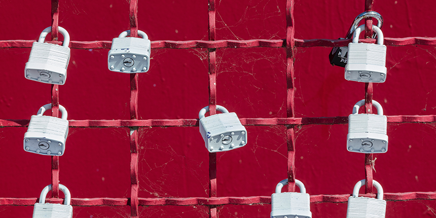 Grey padlocks attached to a red grid fence.
