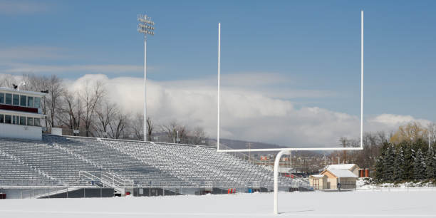 American football field end zone under winter snow, cold and empty post season sports stadium in sunlight under blue skies, Pennsylvania, PA, USA.