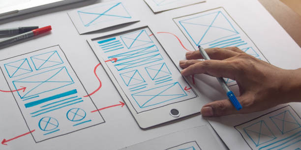UX designer sketching out mobile experience wireframe on paper