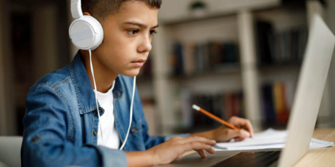 Adolescente escuchando música mientras hace los deberes.