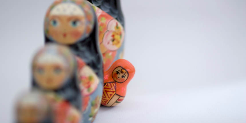 Formation of Russian dolls, with one toddler doll peeking at what's ahead, standing out from the crowd