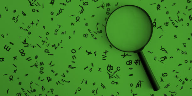 Lupa rodeada de alfabetos de madera sobre fondo verde