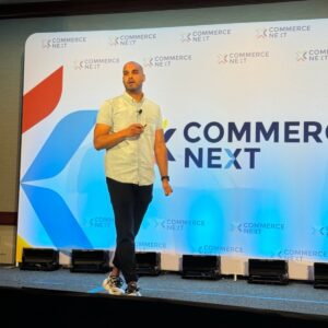 Man speaking on stage at Commerce Next event.