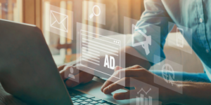Person typing on a laptop with digital marketing icons overlayed, including email and advertising symbols.
