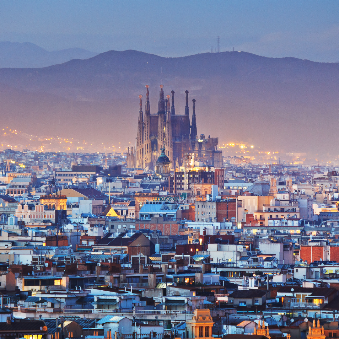 Skyline of Barcelona with the Sagrada Familia in the background at dusk.