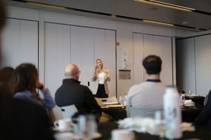 A person speaking to an audience in a conference room setting.