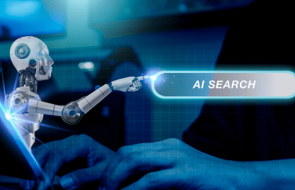 A robot pointing to a glowing "AI SEARCH" button on a digital interface, with a person's hands typing on a keyboard in the foreground.