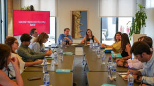 Reunión de personas en una sala de conferencias con pantalla que muestra "MARKETINGDIRECTO.COM MKD".