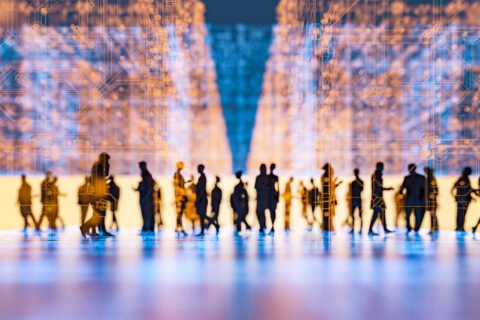 Silhouettes of people walking in a digital, futuristic environment with glowing orange circuit patterns.