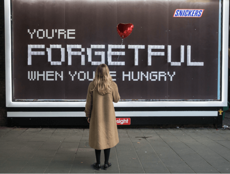 Snickers billboard with girl holding heart balloon