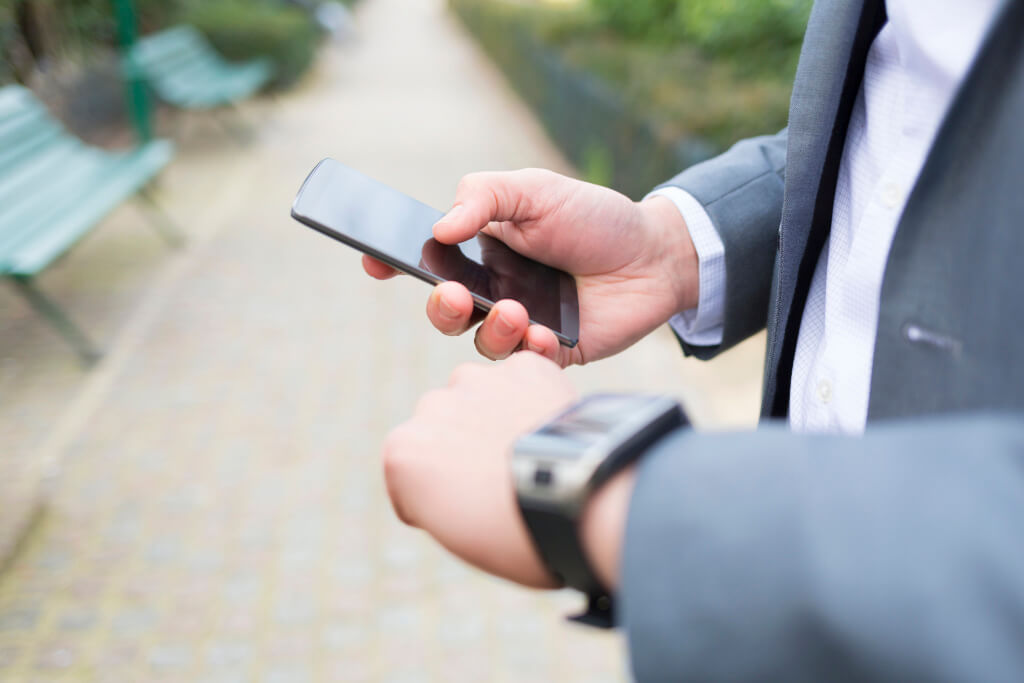 Man with Mobile phone connected to a smartwatch. Close-up hands
