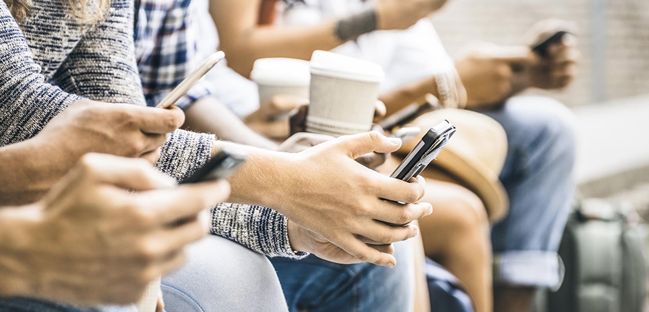 Une rangée de gens assis, utilisant tous leur téléphone intelligent