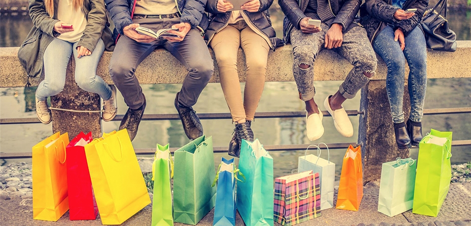 Shopping bags arranged beneath a row of people sitting on a large concrete handrail