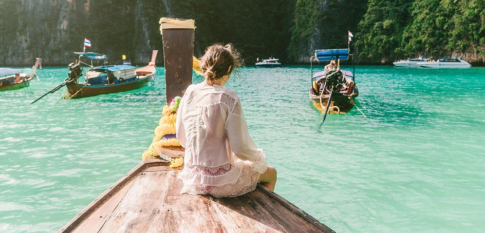 Woman sitting on the deck of a small wooden boat in tropical waters