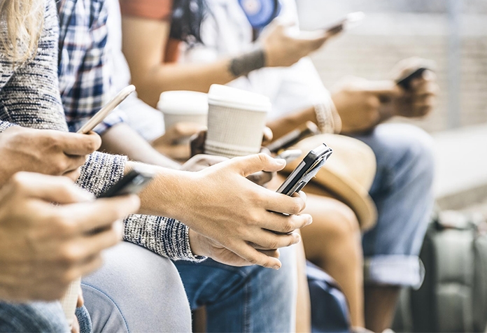 Una fila de gente sentada usando sus smartphones