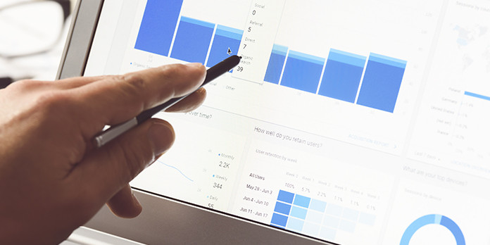Hand pointing stylus at a graph on a laptop screen