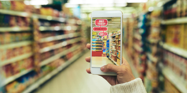 Gros plan d’une jeune femme faisant son épicerie dans un hypermarché à l’aide d’une application de réalité augmentée, fond flou