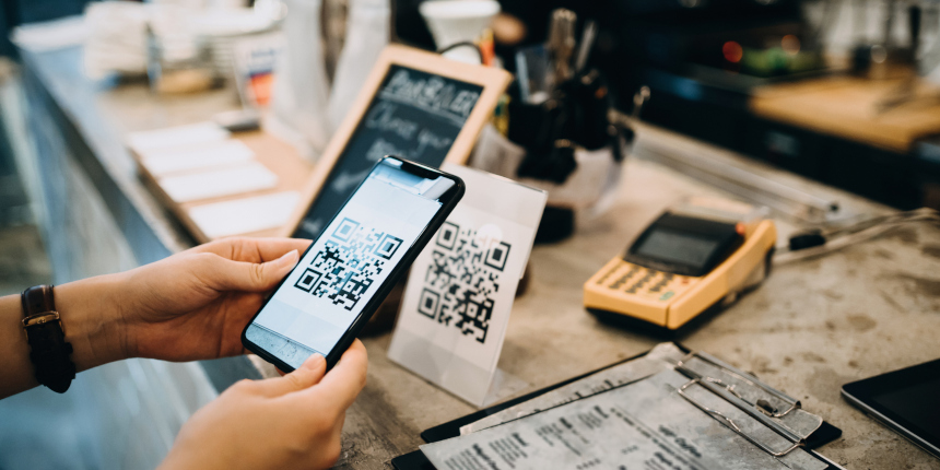 Customer scanning QR code, making a quick and easy contactless payment with her smartphone in a cafe