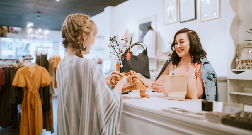 Woman making a purchase from a female cashier at a retail store.