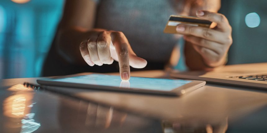 Cropped shot of an unrecognizable businesswoman using her tablet to make payments while working late in the office